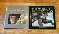 Both hardcover coffee table books shown side by side on wooden floor, covers visible with animal artwork by Robert Bateman.