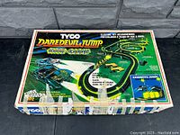 Original box of Tyco Daredevil Jump slot car set with colorful graphics showing night glow track layout, cars, and jump ramp