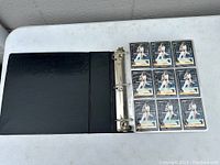Black binder open showing a page with nine identical Barry Bonds baseball cards from Pinnacle brand, depicting him in Pirates uniform at bat.