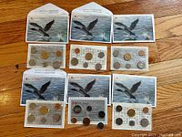 Top-down photo showing six sealed Canadian proof-like coin sets alongside their original Royal Canadian Mint envelopes featuring a flying loon design.