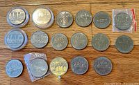 Lot of 17 varied Canadian dollars laid out on wooden surface, some in plastic cases or bags, showing different commemorative designs including Confederation Constitution 1982 and nature scenes