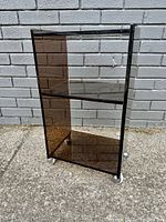 Full view of the bar cart showing its rectangular shape, two shelves, lucite frame and smoked glass panels on sides.