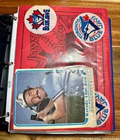 Red binder cover interior with two circular Toronto Blue Jays logo decals and one card partially inserted