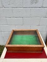 Top-down view of the vintage wooden display case showing glass top and green felt interior.