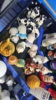 Top view photo showing multiple animal-themed salt and pepper shakers including cows, pigs, chicken, bear shapes, yellow beehive, rooster, and dog shakers.