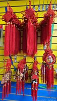 Large red tassels with knotted tops and hanging strands displayed on a wall