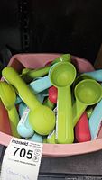 Multiple colored ice cream scoops in a pink container, showing bright lime green, light blue, and red scoops stacked together.