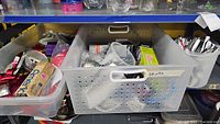 Plastic container and metal perforated bin filled with assorted kitchen gadgets and utensils