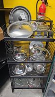 Metal shelving unit with pots and glass lids on shelves, measuring 25x16x54 inches.