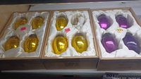 Box with two sets of six yellow glass ornaments each, satin-lined box interior, metal tops with hangers.