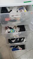 Three drawers containing assorted socks in various colors and patterns.