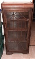Front view of wooden bookshelf cabinet with glass door closed, showing decorative wooden grid on glass.