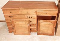 Photo of the lower cabinet section with drawers and two Shaker-style doors, showing the wood grain and metal handles.
