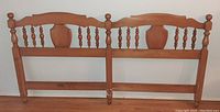 Front view of solid maple king size headboard with spindle and shield design, showing wear at bottom
