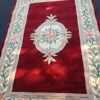 Full view of the 5x8 wool rug showing the central floral medallion on red background with floral border.