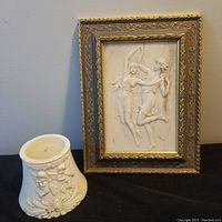 Full view of marble plaque in gold-tone frame beside white decorative candle holder to show lot contents