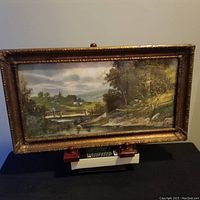 Front view of the antique framed landscape print placed on a stand, showing overall condition and frame details.