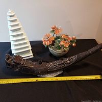 Full view showing all three items: a white ceramic pagoda, a floral arrangement, and a carved dragon item on black cloth background with measuring tape.