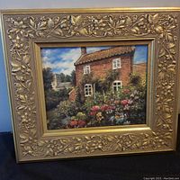 Frontal view of the oil painting showing a rustic cottage and garden in an ornate gilt frame.