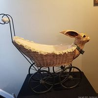 Full view of the vintage wicker bunny buggy with iron wheels and handle, showing its size and shape.
