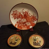 Full view of the decorative Japanese plate and the two smaller round wall plaques arranged on a black surface.