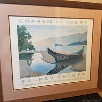 Framed print showing an Indigenous style canoe by the shore with islands and mountains in background
