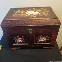 Front view of the large wooden storage box showing hand-painted floral designs on front and a metal latch.