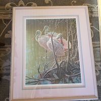 Frontal view of framed offset lithograph depicting three roseate spoonbills in a mangrove