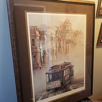 Framed lithograph showing a San Francisco cable car and Victorian buildings in muted tones.