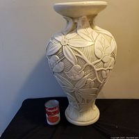 Full view of large ceramic vase next to a Campbell's soup can for size reference, showing the vase's rounded body, neck, and flared rim with embossed floral patterns.