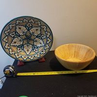 Photo showing both pottery and wooden bowls side by side with measuring tape showing length.