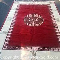 Full view of large red Asian themed wool area rug with central circular medallion and Greek key border.