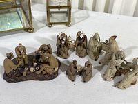 Photo of five Chinese mud men clay figurine tableaus arranged in a group on a surface. Also showing two small rectangular glass lidded boxes with metal frames behind the figurines.