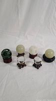 Full set of 6 small crystal spheres on stands, showing variation in size, color, and carved details.