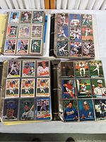 Top-down view of four binders open to pages showing baseball player cards from 1980s-90s, displaying a variety of players in uniform action poses and portrait style cards.