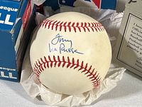 Photo of autographed baseball signed by Tony LaRussa in blue ink, nestled in tissue paper inside a rawlings baseball box.