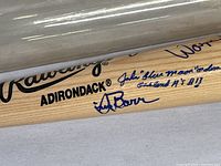 Close-up of signatures on Rawlings Adirondack bat including 'John "Blue Moon" Odom' signature in blue ink.