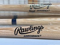 Close-up of Rawlings Adirondack logo on natural wood baseball bat in protective tube.