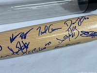 Close-up of the baseball bat’s barrel showing multiple signatures by San Francisco Giants players and others in blue ink.