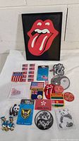 Overview of the lot showing framed Rolling Stones logo and various patches including flags, panda, dragon, and circular red patches.