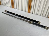 Full length of samurai sword and its black wooden sheath with metal caps
