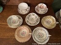Eight assorted porcelain teacup and saucer sets on wooden surface