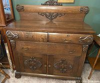 Front view of oak sideboard showing two upper drawers, loose bottom drawer, double-door cabinet and carved gallery back