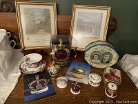 Front view of the entire collection showing framed prints, crowns, tins, cups, and postcards arranged on a wooden surface.