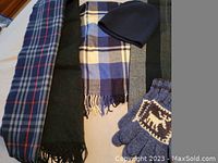 Photo showing three scarves, one black knit hat, and one pair of gloves with a reindeer design.