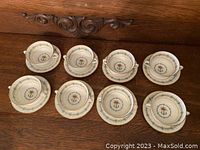 Eight matching soup bowls on paired underplates displayed on wooden surface.