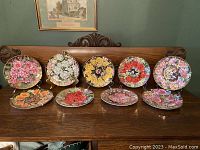 Front view of all 10 decorative Royal Worcester floral plates showing varied colorful floral patterns with 22K gold trim.