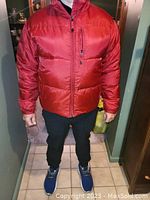 Front view full zipper closed showing red puffer jacket on model.