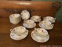 Photo shows 12 cream colored fruit nappies with handles and intricate floral design in burgundy, brown, blue colors.