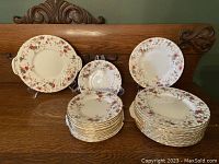 Full view of the 33-piece set with stacked 12 dinner plates 8 inches, 12 smaller plates 6.25 inches, and cake plate 9.5 inches on display furniture backdrop.